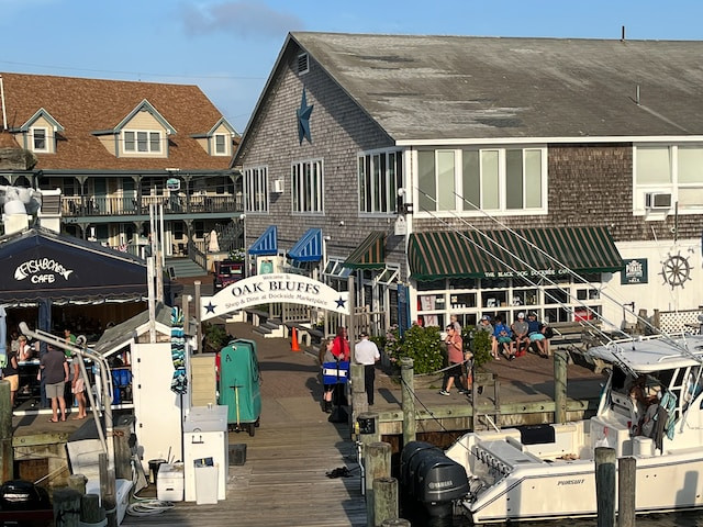 A busy harbor scene.  A boat is docked, people are walking about, shops in the background.