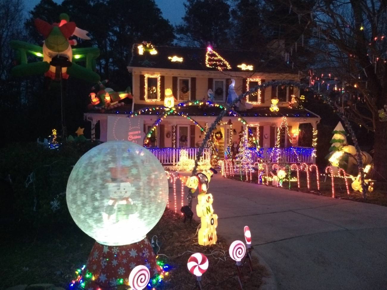 Candy canes along the driveway, snow globe in front of house, lots of christmas lights on home.