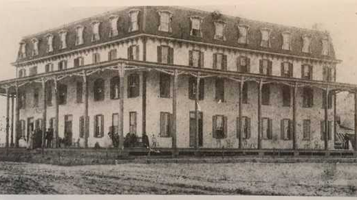 A black and white historic photo of a hotel from the 1870s.
