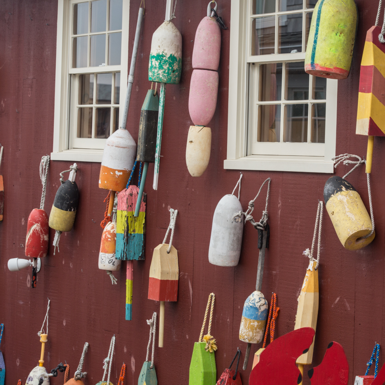 Red wall, fisherman's colorful buoys hanging from it.