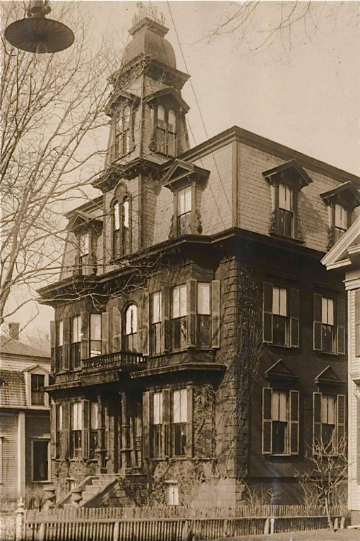 A sepia photo.  A historic mansion, it is 3 stories high, with an additional  fourth-level turret on top.